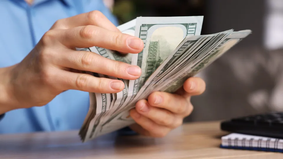 Dólar desacelera alta ante real com fluxo comercial positivo